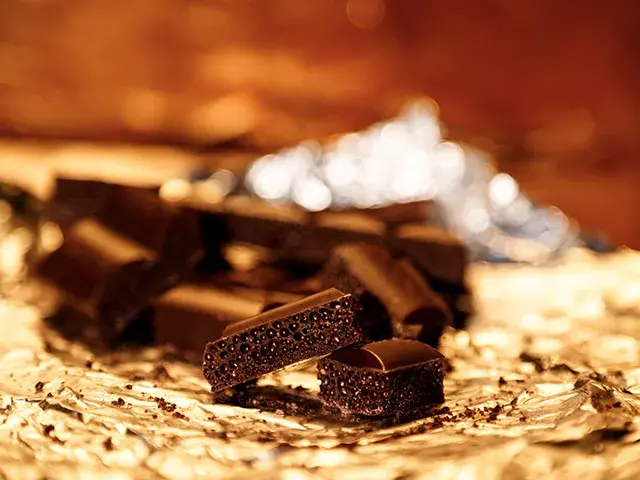 Trocitos de chocolate negro poroso sobre papel aluminio.