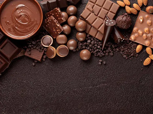 Variedad de chocolates y almendras sobre fondo oscuro.