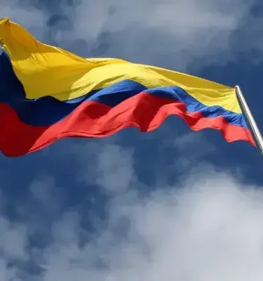 Bandera de Colombia ondeando al viento bajo un cielo azul