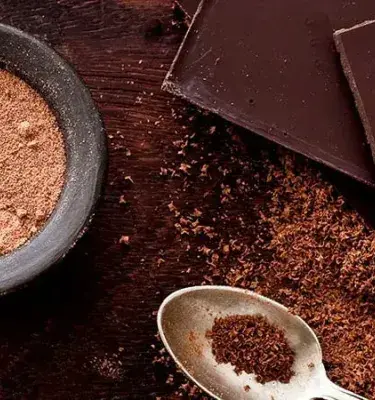 Chocolate negro en trozos y cacao en polvo sobre madera.