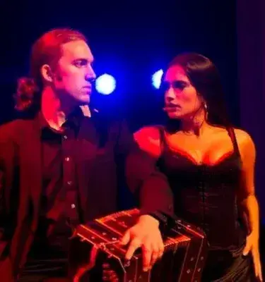 Pareja de tango con un bandoneón en un escenario. ¡Qué elegancia y pasión se sienten! 