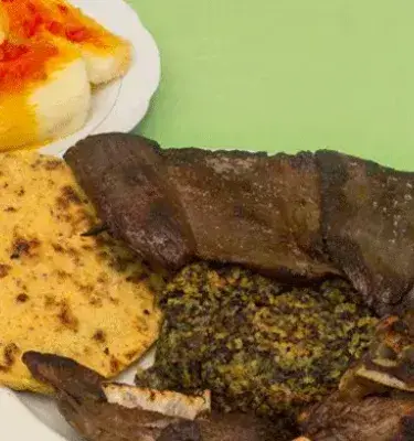 Plato de cabro al horno con arepa, pepitoria y yuca.