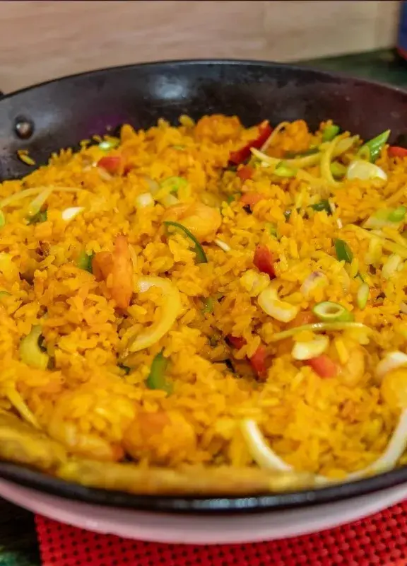 Arroz típico de la Costa Caribe de Colombia, servido en un sartén con vegetales y plátano frito